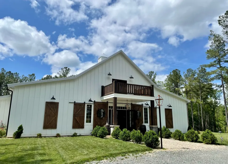 The white barn and its balcony above a green lawn