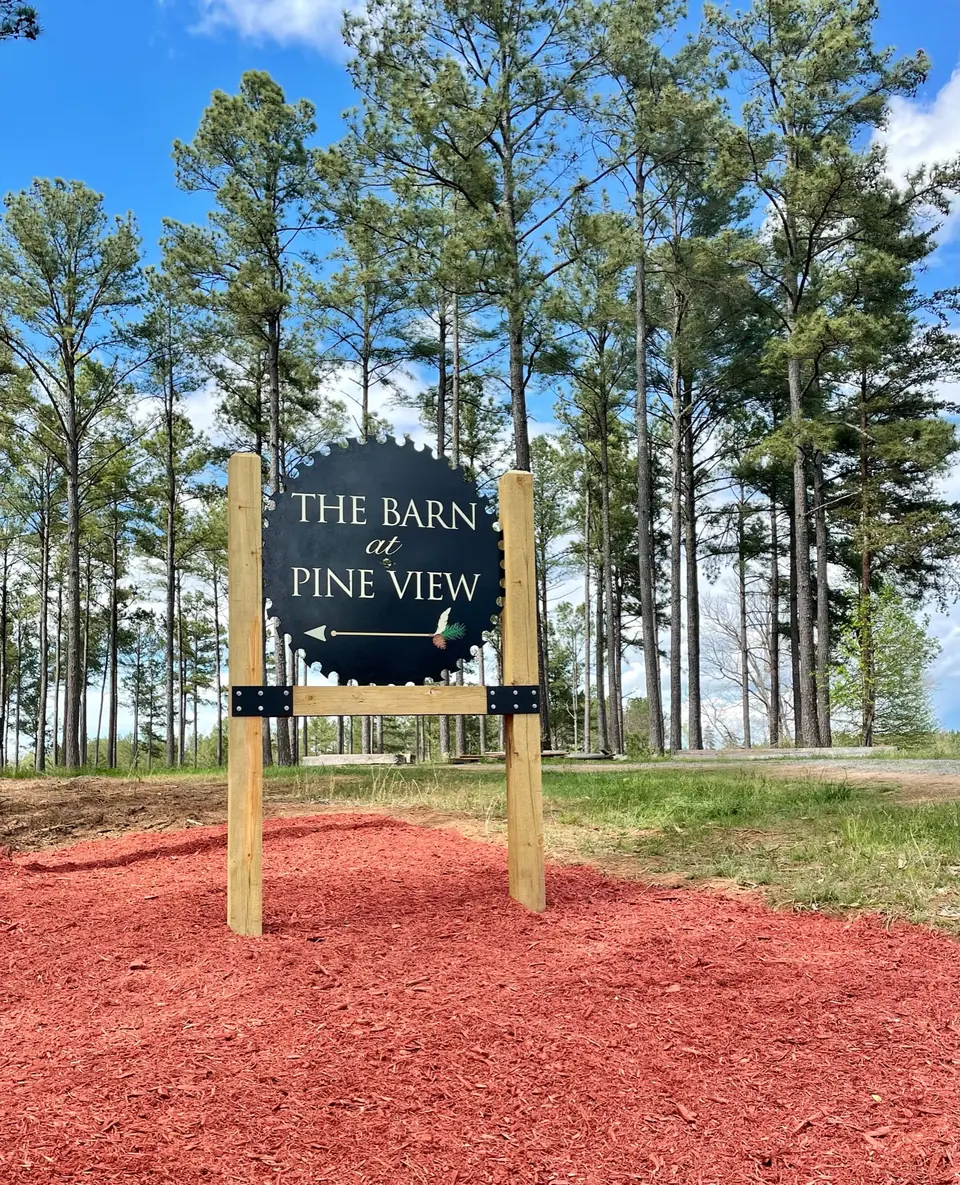 The Barn at Pine View sign at the farm entrance among the pines