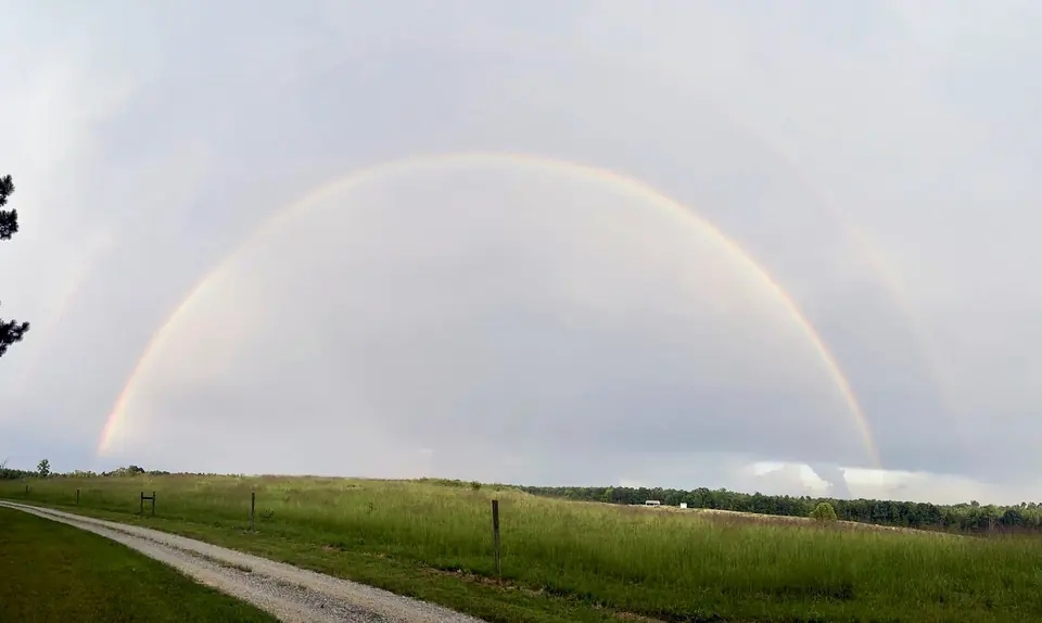 A full rainbow arching over the open pasture